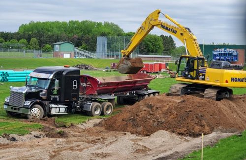 excavator moving dirt into truck